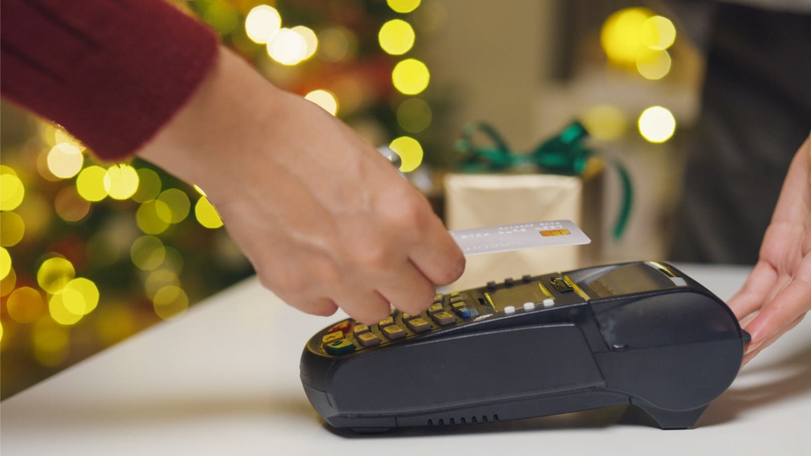close-up of person swiping credit card in shop during holidays
