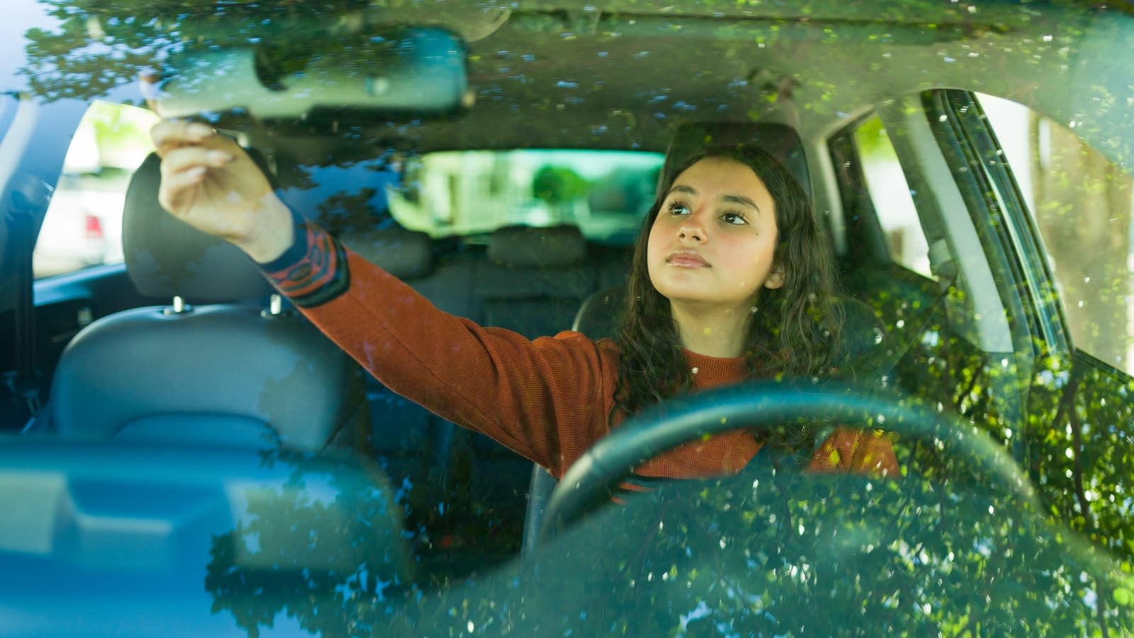 Female teen adjusting rear view mirror in car