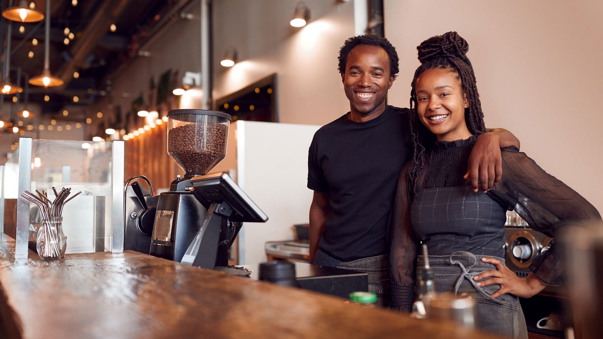 Young business owners behind counter of their coffee shop.