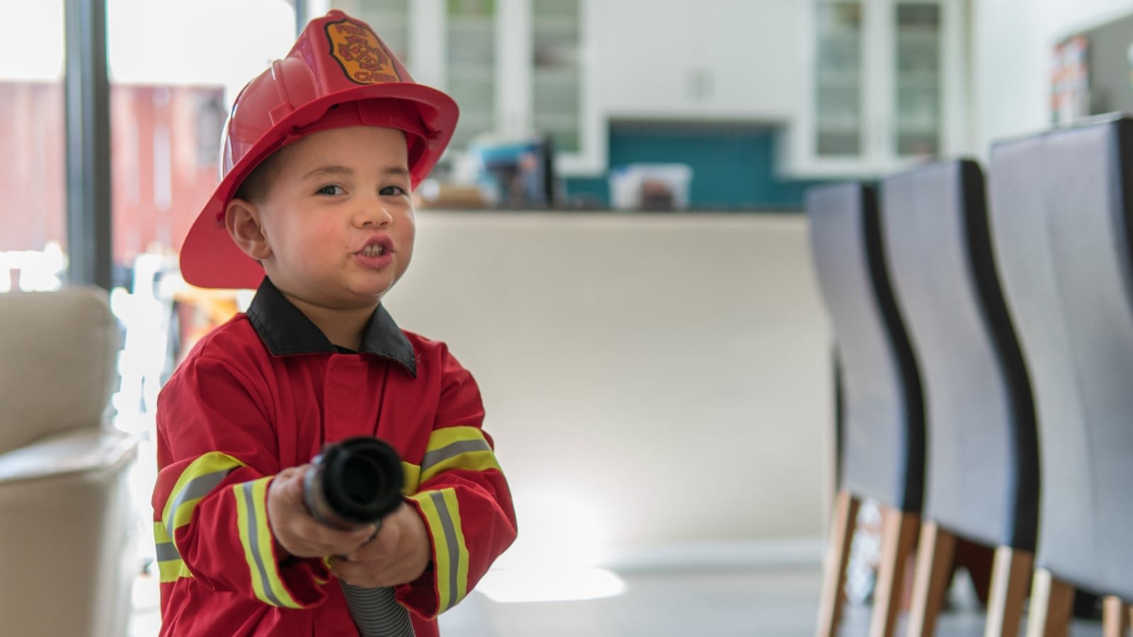 little boy dressed as firefighter in home