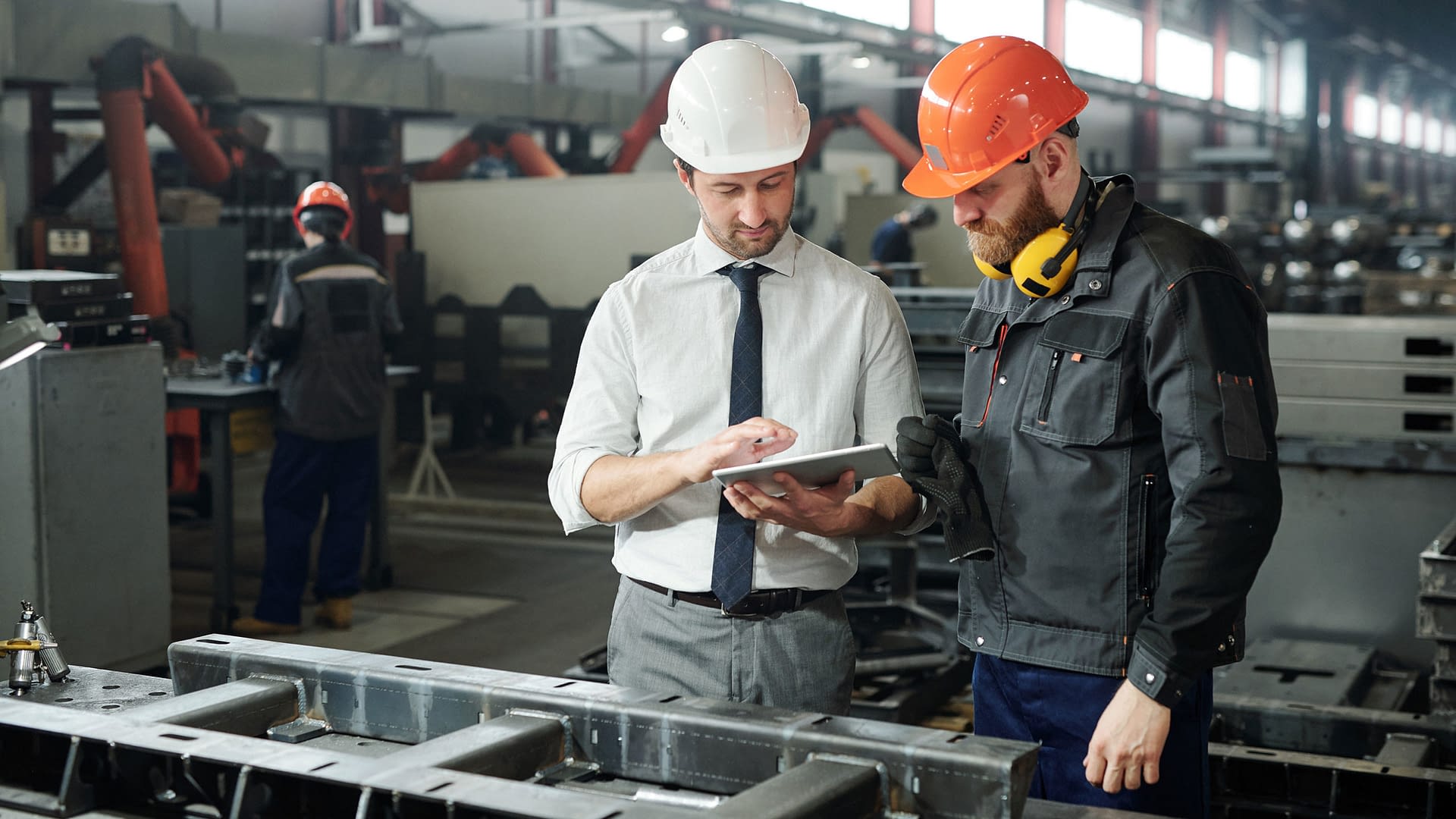 Foreman and worker in conversation at a manufacturing facility.